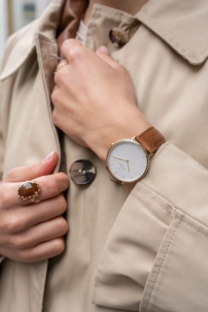a woman wearing a trench coat and a watch